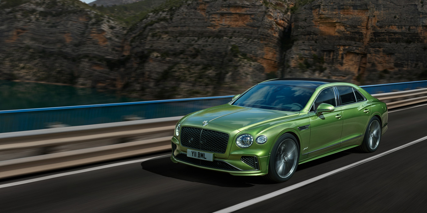 Bentley Milano Bentley New Flying Spur Speed v8 hybrid sedan driving dynamically on a mountain road in Tourmaline Green paint