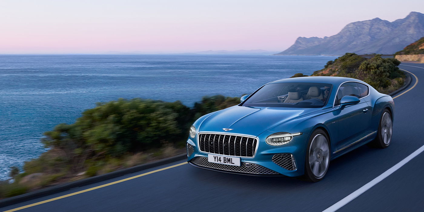 Bentley Milano New Bentley Continental GT Azure coupe in Light Windsor blue paint with 22 inch Azure wheels and chrome grill, driving dynamically by the sea