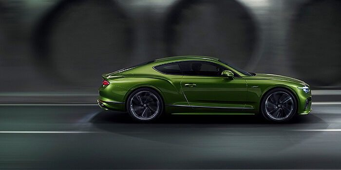  Bentley Milano Bentley Continental GT coupe in Tourmaline Green paint driving in profile on a dark road