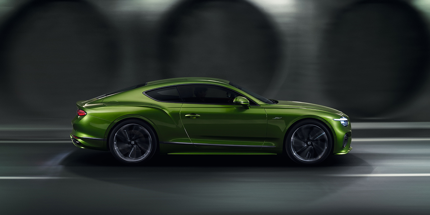 Bentley Milano Bentley Continental GT coupe in Tourmaline Green paint driving in profile on a dark road